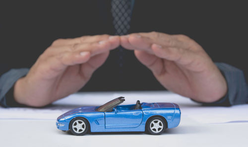 Midsection of businessman with toy cars sitting at desk in office