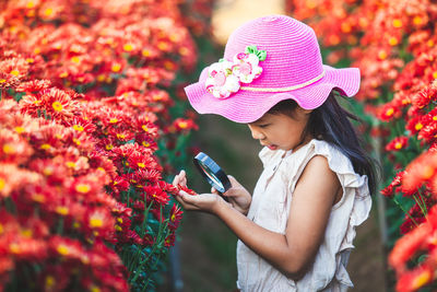 Side view of girl holding pink flower