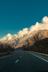 Road by mountains against blue sky