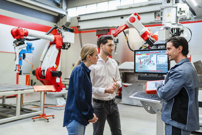 Colleagues discussing together standing at robot factory