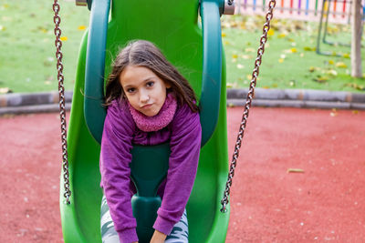 Portrait of girl sitting on swing at park