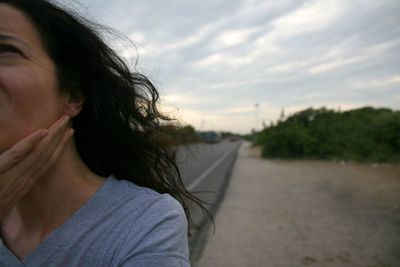 Close-up portrait of young woman with long hair against sky during sunset