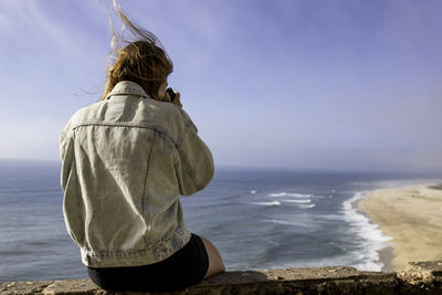 Rear view of woman photographing sea against sky