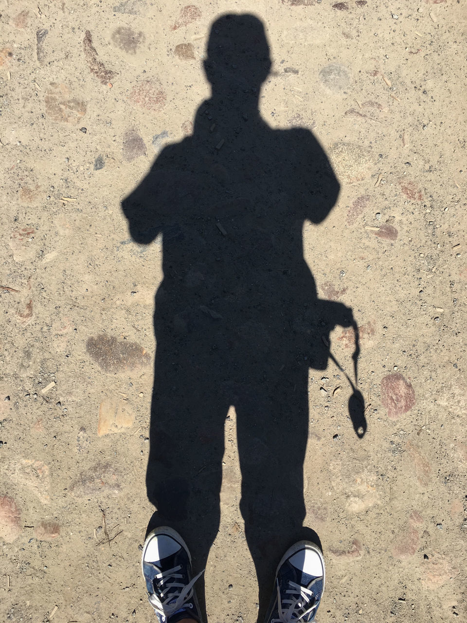 LOW SECTION OF MAN WITH SHADOW STANDING ON STREET