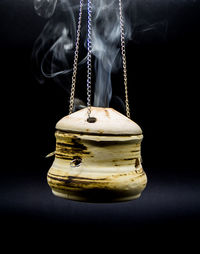 Close-up of ice cream hanging on rope against black background