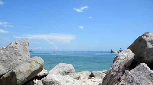 Rocks by sea against blue sky