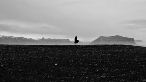 Silhouette woman walking on land against sky