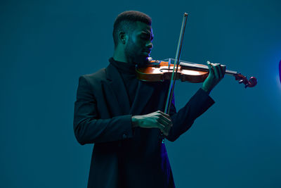 Midsection of man playing violin against white background