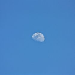 Low angle view of moon against blue sky