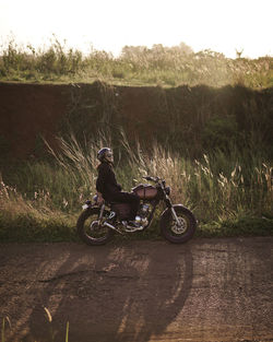 Smiling woman sitting on motorcycle against grass