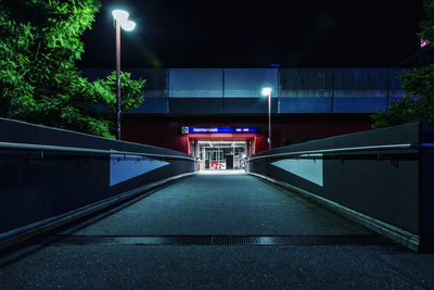 Empty road leading towards building at night