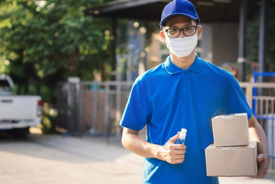 Portrait of young man standing against blue wall