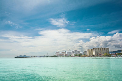 Scenic view of sea by buildings against sky