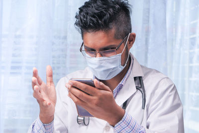 Doctor wearing mask using smart phone at clinic