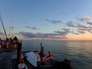 Man sitting on sea against sky during sunset