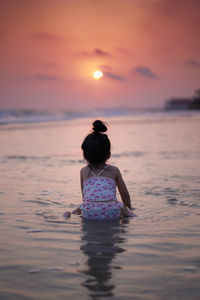 Rear view of woman on beach during sunset