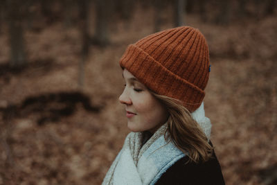 Side view of woman with knit hat and eyes closed at park during autumn