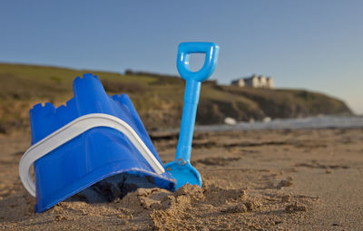 Close-up of sunglasses on beach against clear blue sky