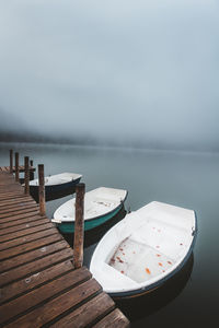 Wooden jetty on pier by lake against sky