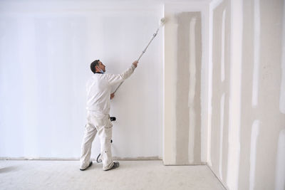 Painter painting wall with roller at construction site