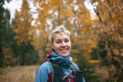 Portrait of smiling young woman in forest during autumn