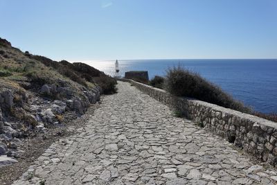 Footpath amidst sea against clear sky