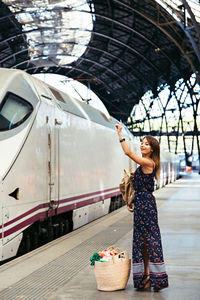 Beautiful woman gesturing while standing on platform at railroad station