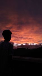 Rear view of silhouette man looking at sunset