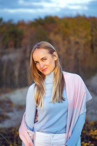 Portrait of smiling young woman standing on land