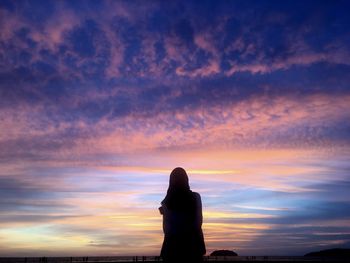 Silhouette woman standing against orange sky