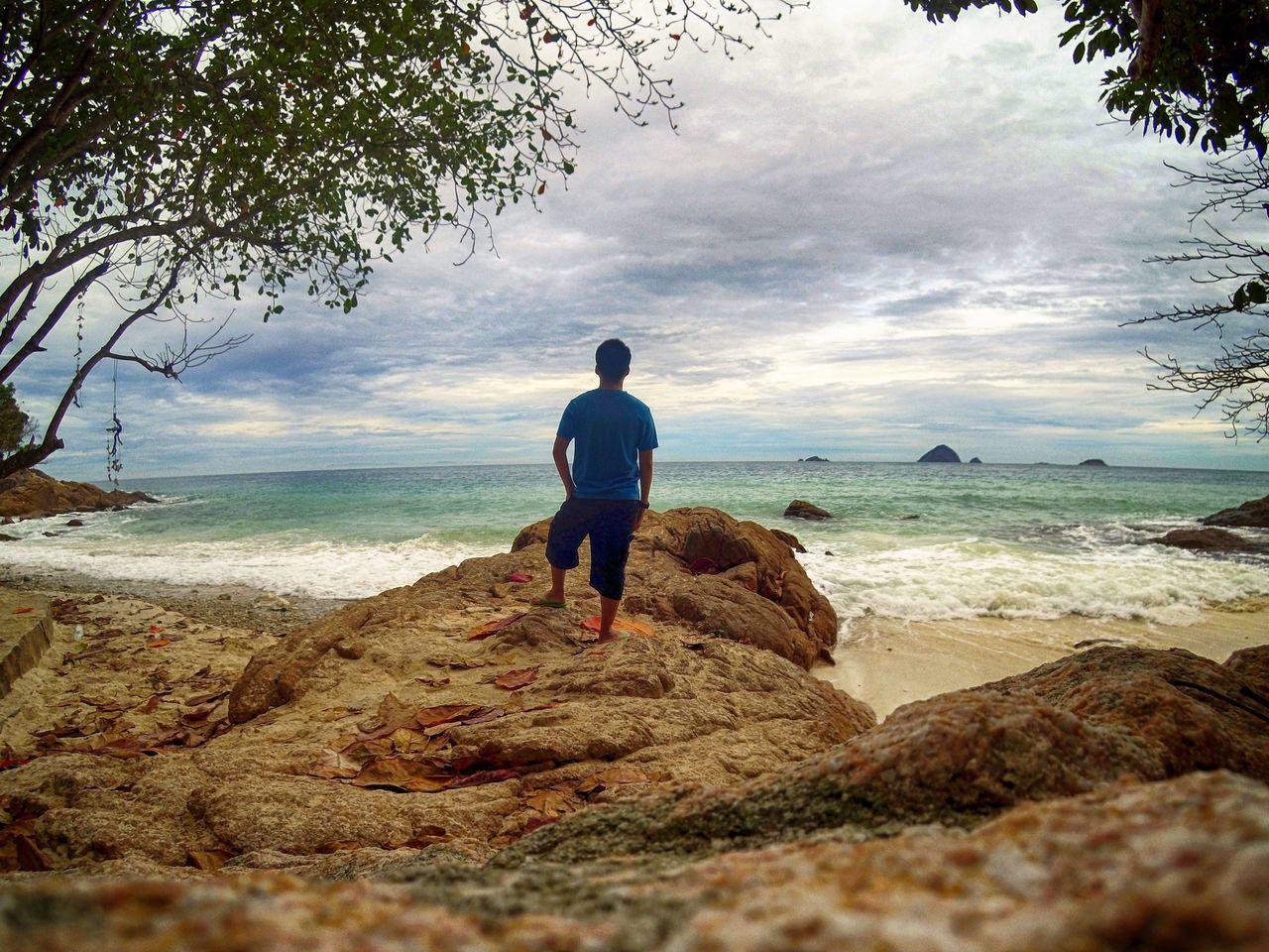 REAR VIEW OF WOMAN STANDING ON BEACH