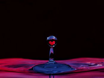 Close-up of water splashing on table against black background