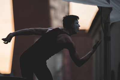 Side view of young man standing at home