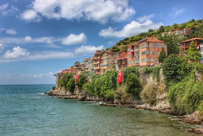 Scenic view of sea by houses on cliff against sky