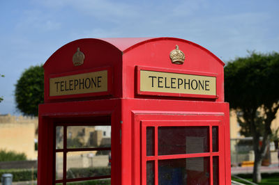 Close-up of telephone booth sign against sky