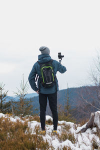 Rear view of man photographing during winter