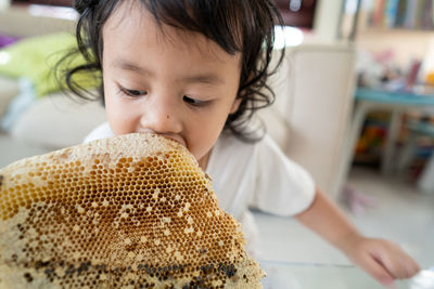 Close-up of girl eating honey from honeycomb