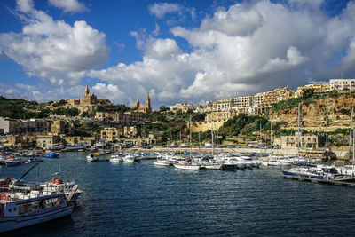 Sailboats moored in river against buildings in city