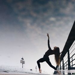 Woman with arms outstretched against sky