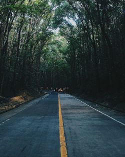 Empty road amidst trees against sky