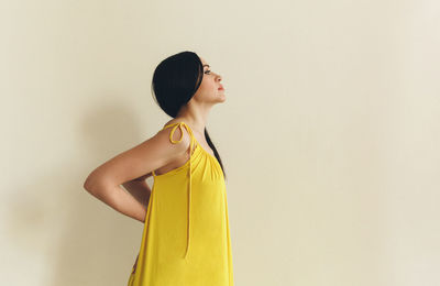 Portrait of young woman standing against wall