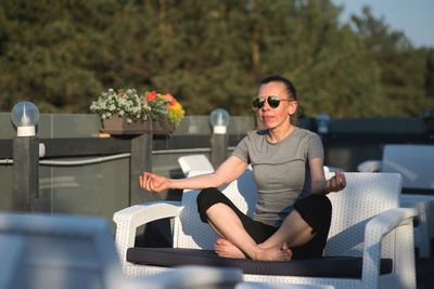 Mature woman meditating while sitting on sofa