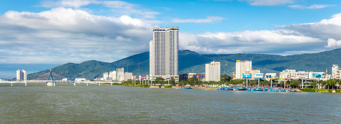 Sea by city buildings against sky