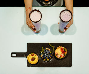 Cropped hands of woman holding drinks on table