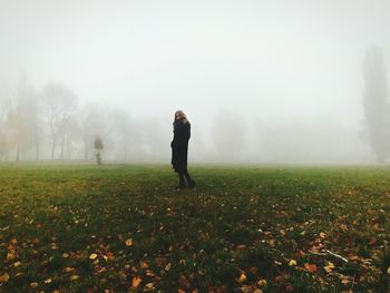 Full length of woman standing on field during foggy weather