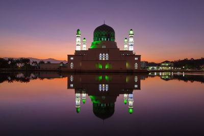 Reflection of illuminated building in lake at sunset