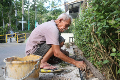 Side view of man working at his plant box