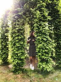 Full length of woman standing by tree