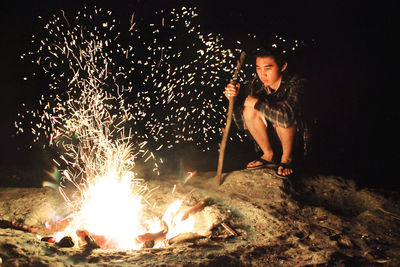 Young man sitting by campfire