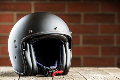 Close-up of helmet on table against brick wall